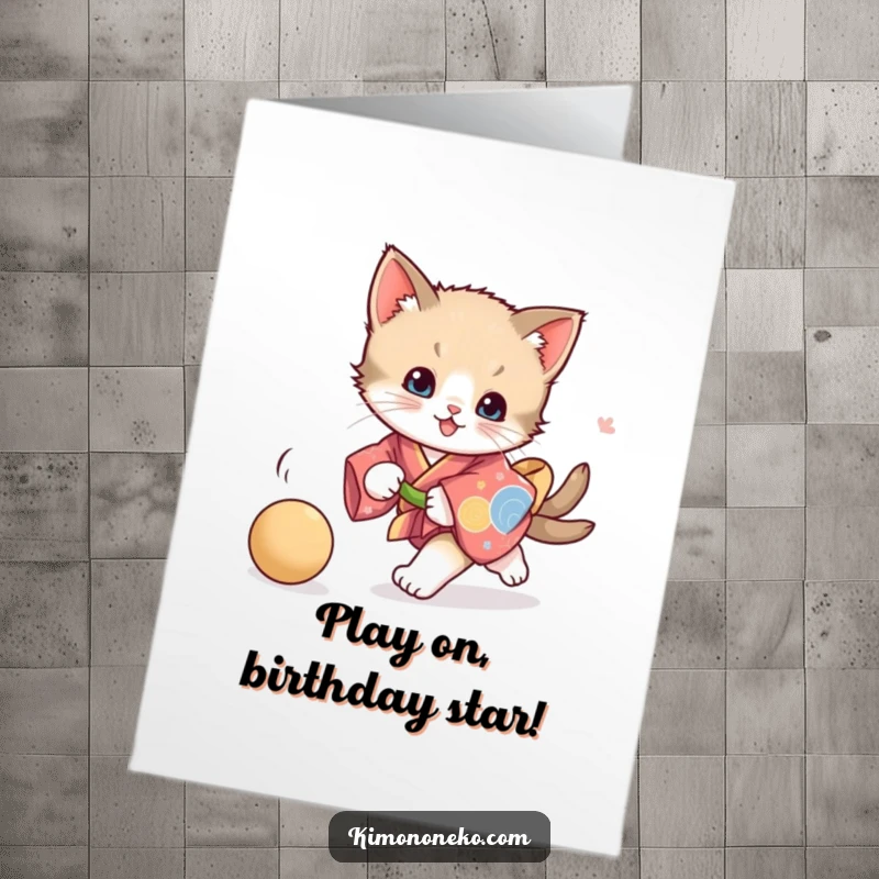 Funny Free Printable Kitten Birthday Card showing a playful kitten in a vibrant kimono, joyfully chasing a ball.